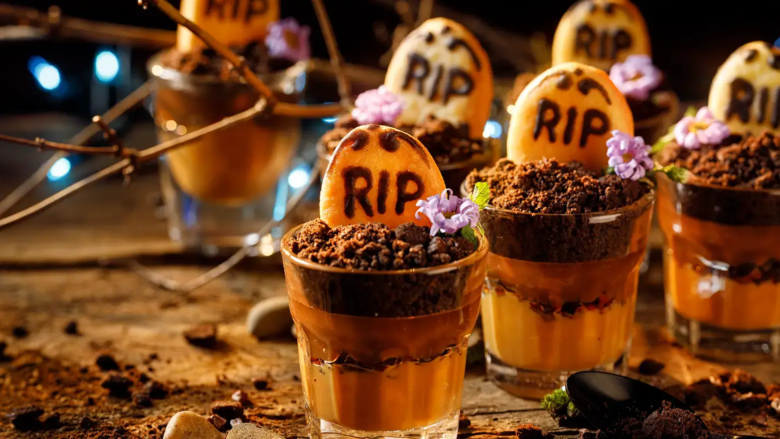 Halloween dessert pudding cup topped with crushed cookies and cookie tombstone