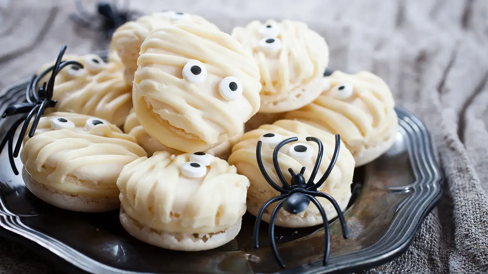 macarons decorated to look like mummies with white chocolate drizzle